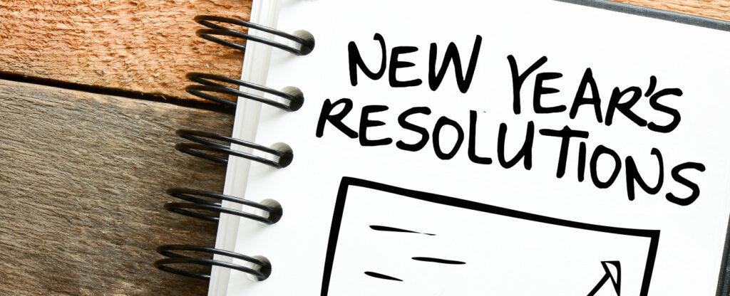 Notebook with "New Year's Resolutions" written on a page, spiral binding visible.