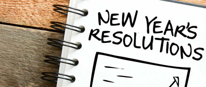 Notebook with "New Year's Resolutions" written on a page, spiral binding visible.