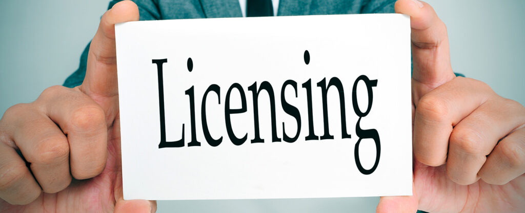 Hands holding a white card with the word "Licensing" in bold black letters.