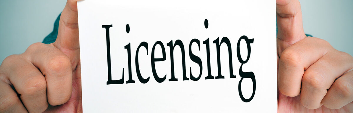 Hands holding a white card with the word "Licensing" in bold black letters.