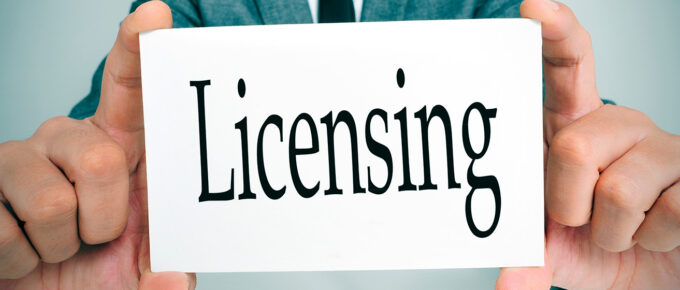 Hands holding a white card with the word "Licensing" in bold black letters.